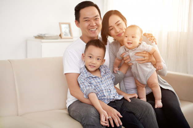 Loving asian couple posing on couch at home with young son and baby Free  Photo - Nohat - Free for designer